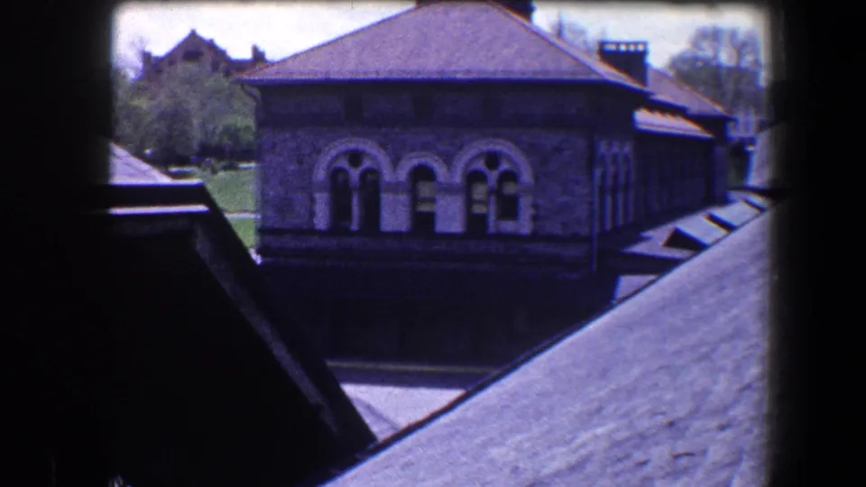 1960 Baltimore home-movie view of a stone building with arched windows seen from above across dark sloping roofs.