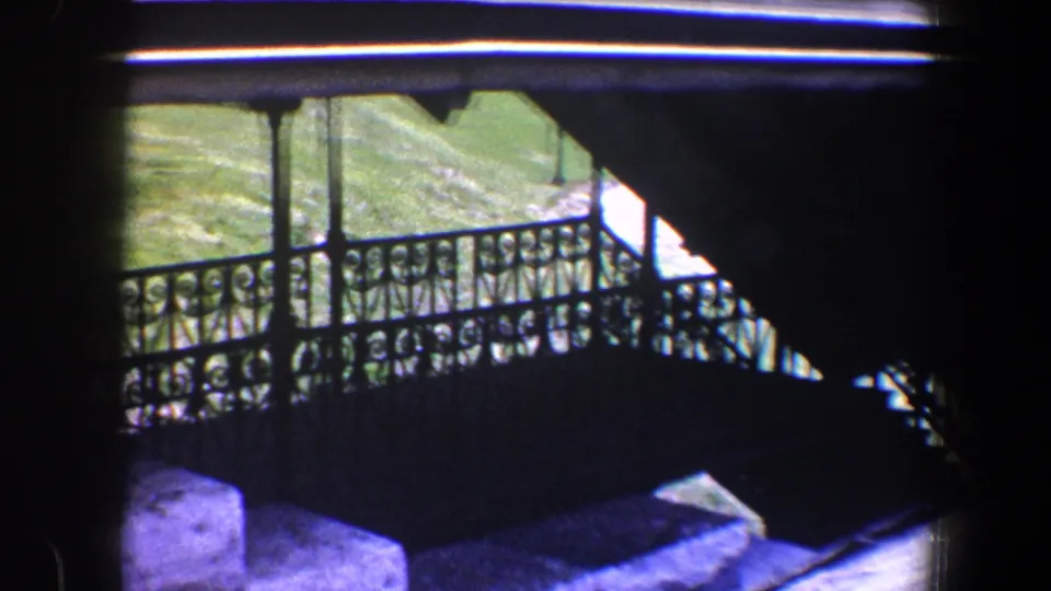 Elevated 1960 Baltimore view of an iron-railed exterior stair, grassy courtyard, and nearby sloped roof.