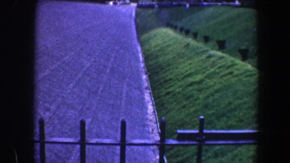 1960 Baltimore balcony view with railing posts crossing a pale path and green hillside beyond.