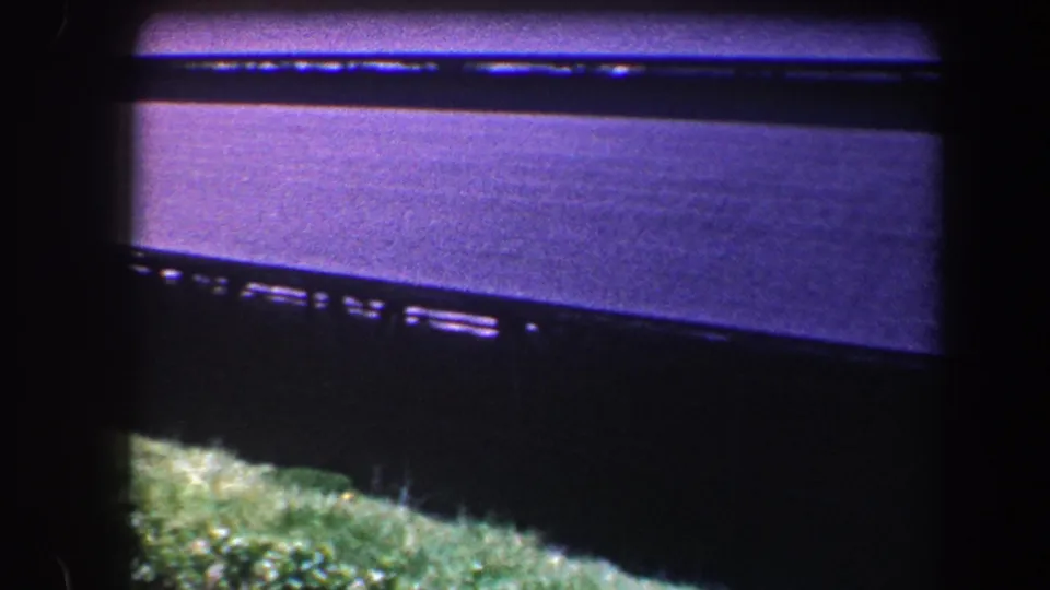 1960 Baltimore 8mm frame showing a dark roof surface, narrow grass strip, and pronounced vignetted film border.