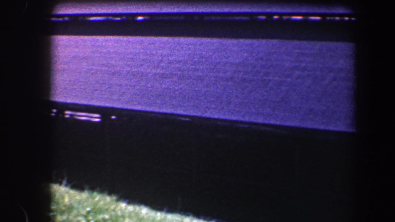 1960 Baltimore 8mm frame showing a dark-edged view of a roof or canopy surface with a small grassy foreground patch.