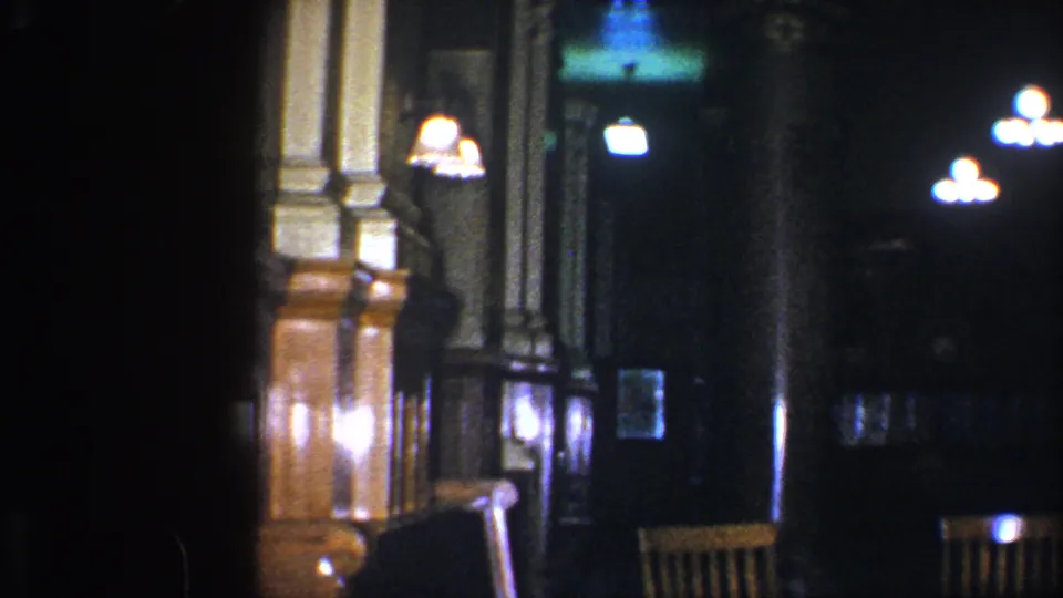 1960 Baltimore public library interior in soft focus, with a wood railing, pale columns, hanging lights, and dark recesses in the hall.