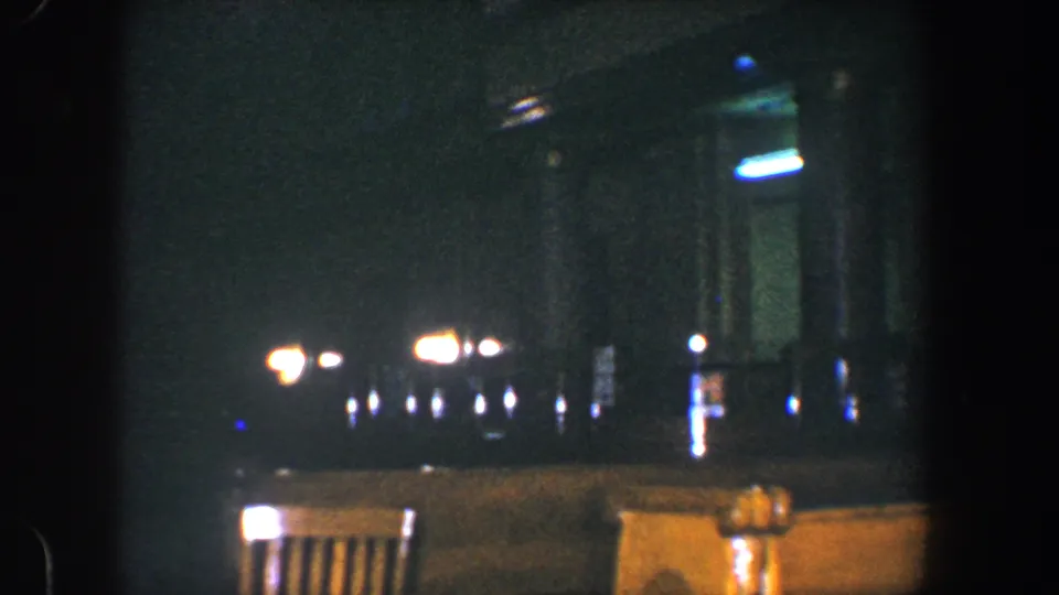 1960 Baltimore 8mm frame with chair backs, clustered blurred lights, and deep shadow across the night setting.