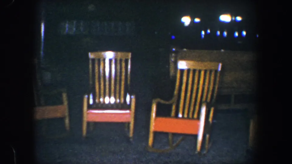 1960 Baltimore 8mm frame showing two prominent rocking chairs and part of a third chair inside a dim private interior.