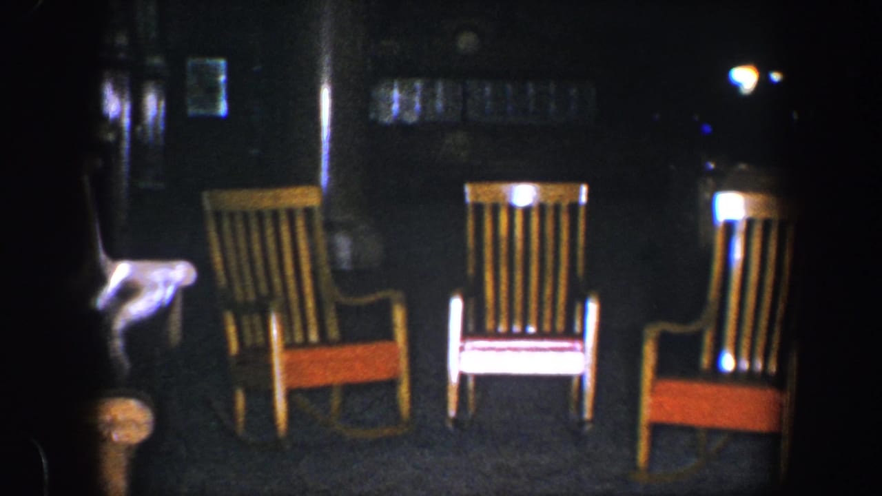 Three empty rocking chairs arranged against a dark background.