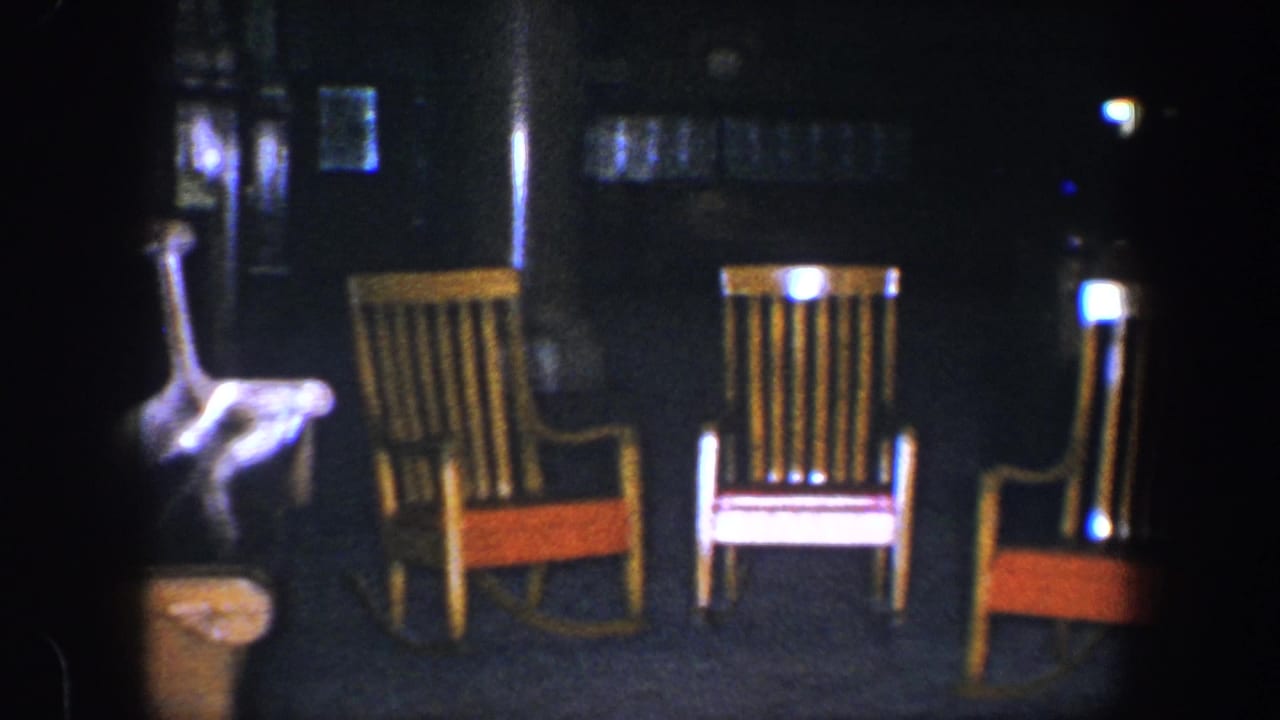 Three empty wooden rocking chairs with red seats are visible in a dim Baltimore night scene from the supplied 1960 8mm clip metadata.
