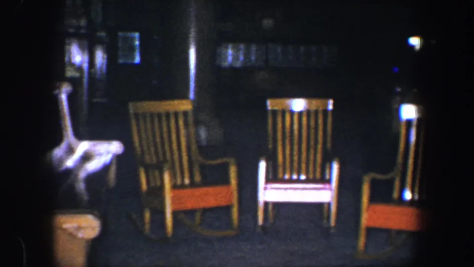 Three empty wooden rocking chairs with red seats are visible in a dim Baltimore night scene from the supplied 1960 8mm clip metadata.