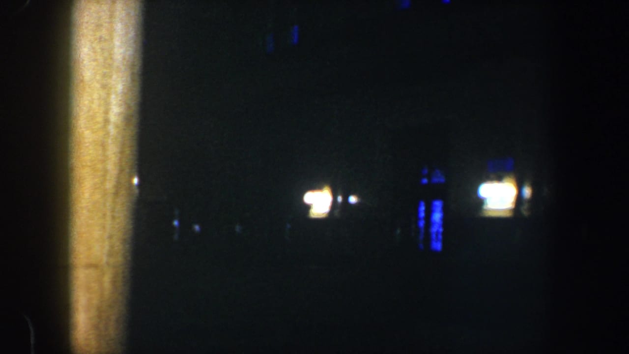 A vertical post divides a very dark night view with small distant lights.