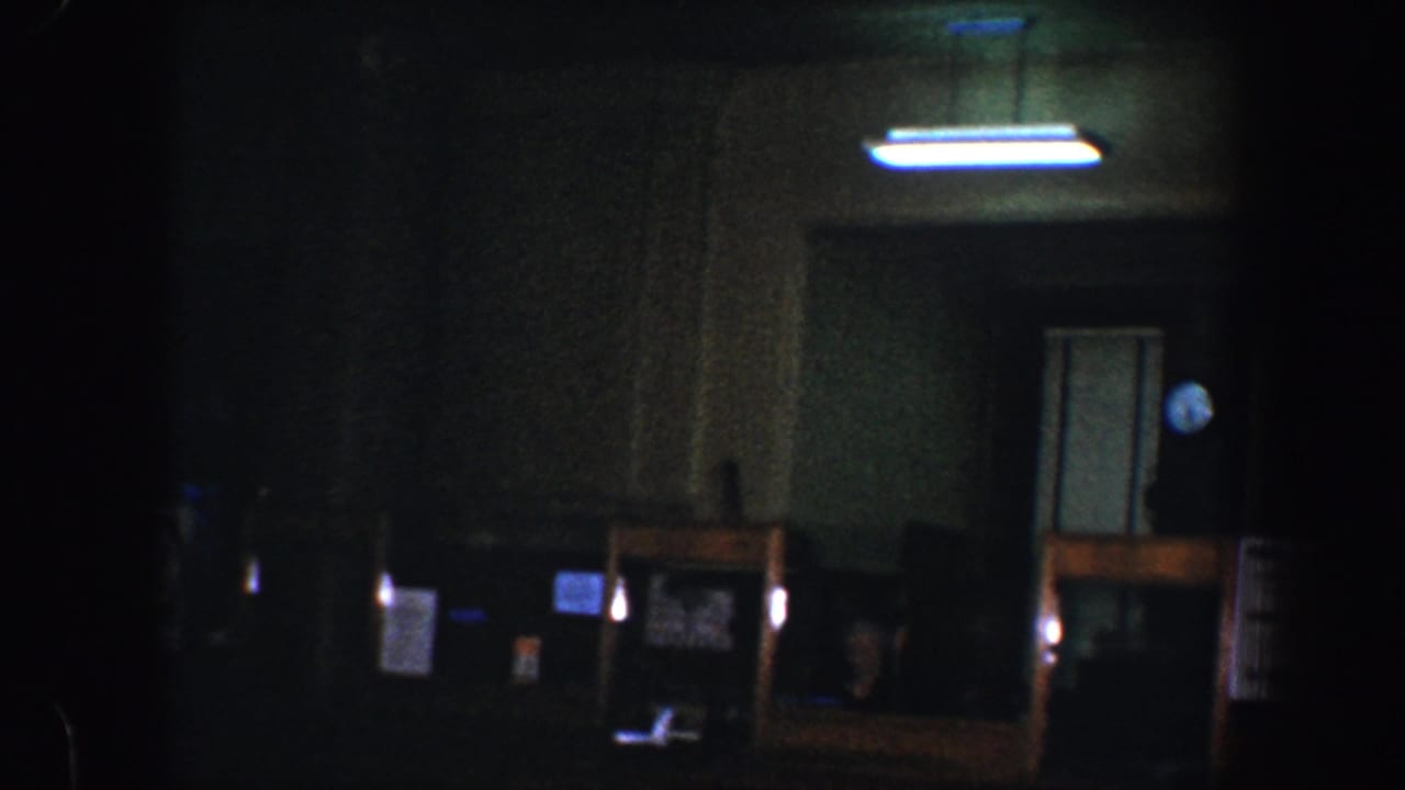 Dim room with fluorescent ceiling light, doorway, wall clock, and dark wood counter.