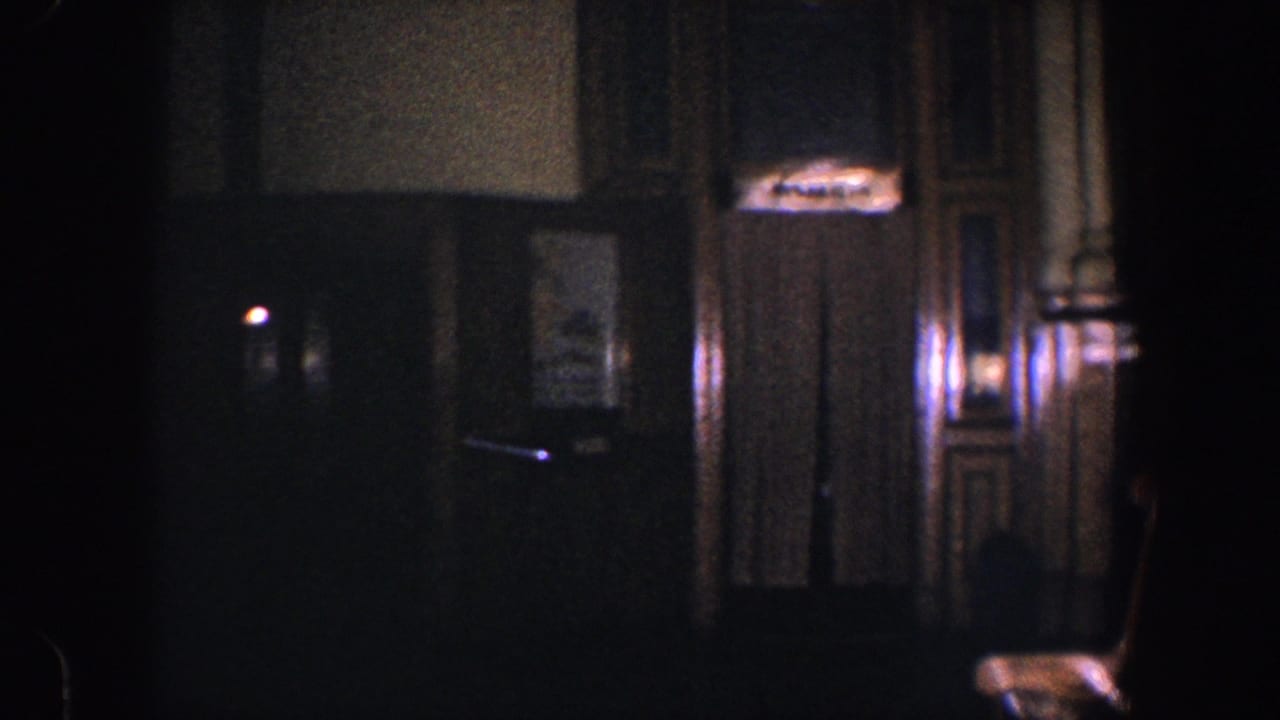 Dim hallway with wood paneling, curtained doorway, small sign, and chair near an elevator area.