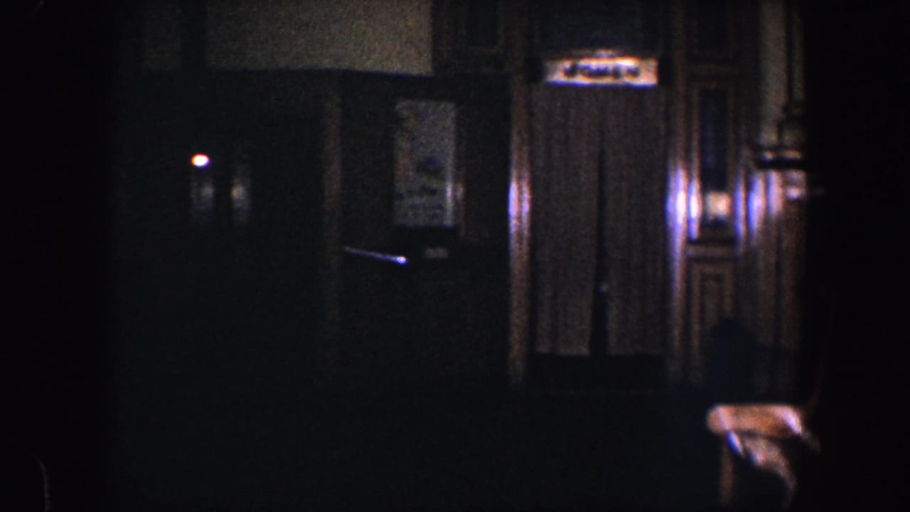 Dim 1960 Baltimore interior view with wood-trimmed hallway, curtained doorway, small elevator sign, and chair in low light.