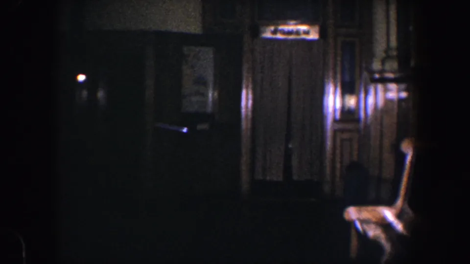 1960 Baltimore hallway frame with a dim corridor, paneled elevator surround, curtained doorway, sign, and chair near the wall.