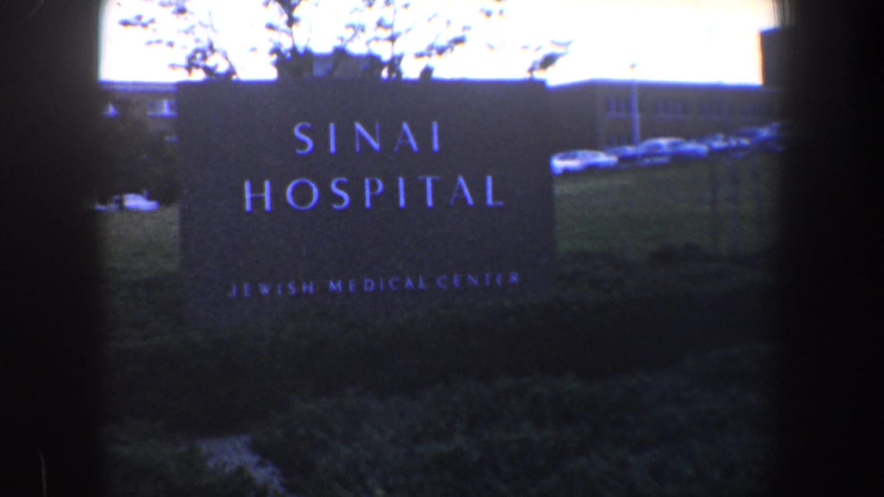 Sinai Hospital sign in front of grass and a low building.
