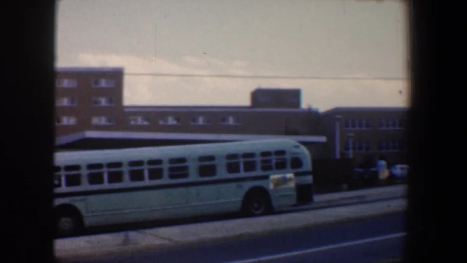The bus fills much of the lower frame as it passes brown brick buildings on a Baltimore city street.