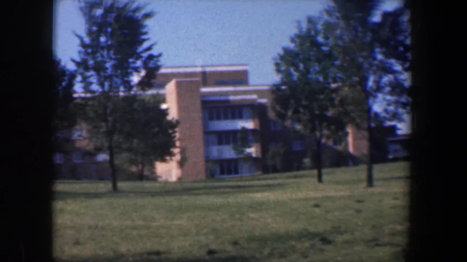 1960 Baltimore exterior view of a brick institutional-looking building across a lawn with trees.