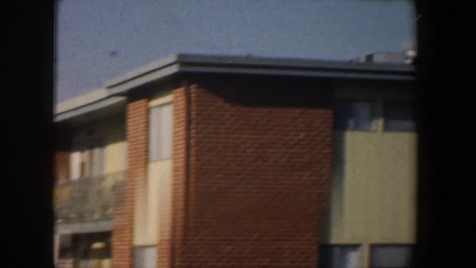1960 Baltimore exterior view of a mid-century apartment building with brick walls, pale panels, and balcony details.