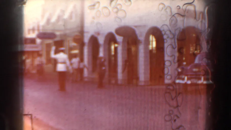 A soft, warm-toned Nassau street view shows arched storefronts, faint pedestrians, and film-edge artifacts.