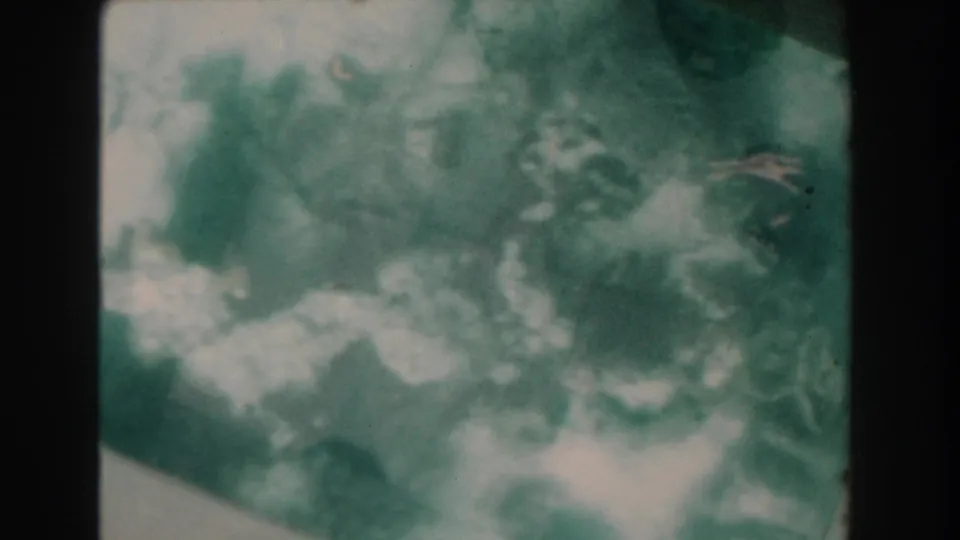 1961 Nassau 8mm frame showing mottled underwater reef or rock texture, pale sand patches, and soft green haze.