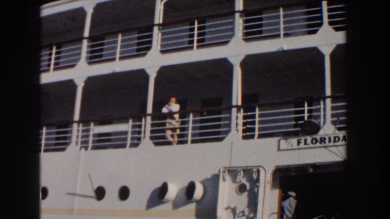 Woman remains at the ship railing above a partial Florida sign and a crew member below.
