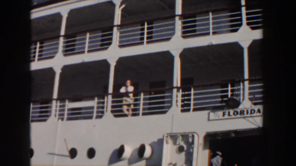 The 1961 Nassau home-movie frame shows the Florida ship decks, with a woman by the railing and circular portholes below.