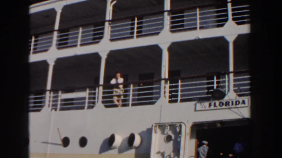 A final 1961 Nassau frame shows the woman on the Florida deck, the ship name partially readable, and a uniformed figure near the lower entrance.