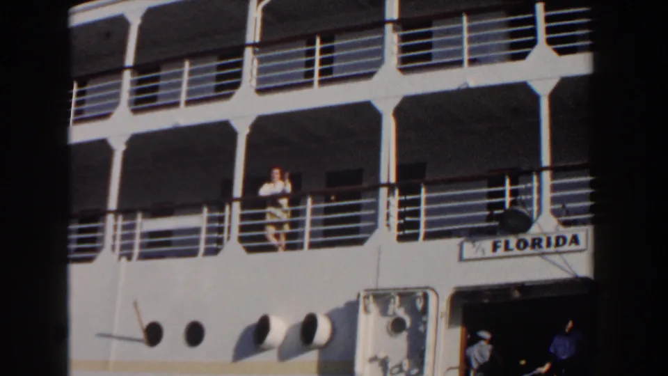 1961 Nassau home-movie frame showing the white cruise ship FLORIDA with passengers near railings and an open lower doorway.