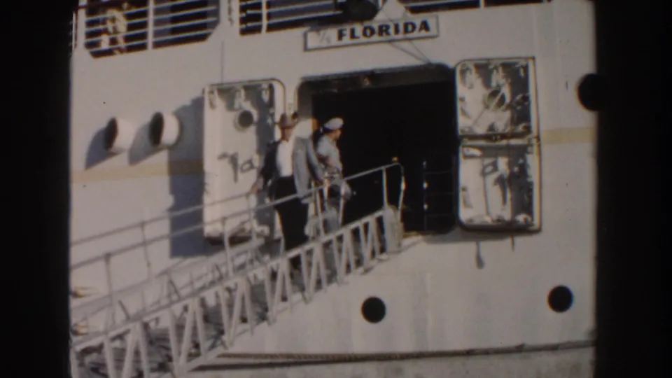 In Nassau, Bahamas in 1961, a man in a light suit and fedora waves from the gangway of a white ship labeled Florida.