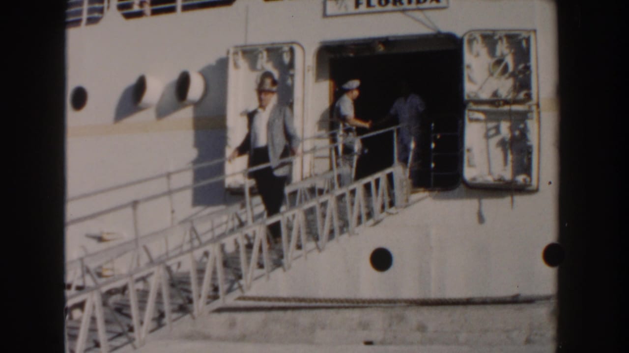 Man stands on the gangway while crew and another person remain at the ship doorway.