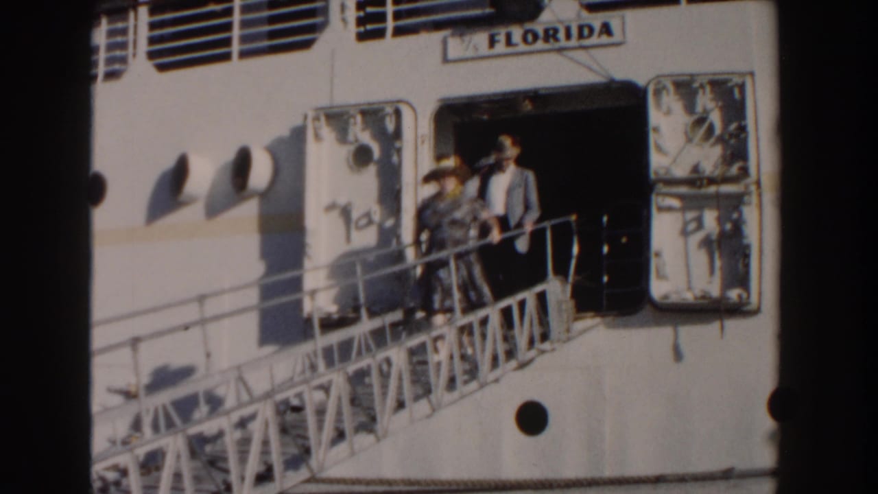 1961 Nassau home-movie frame showing adults on a gangway beside the white ship Florida in bright sun.