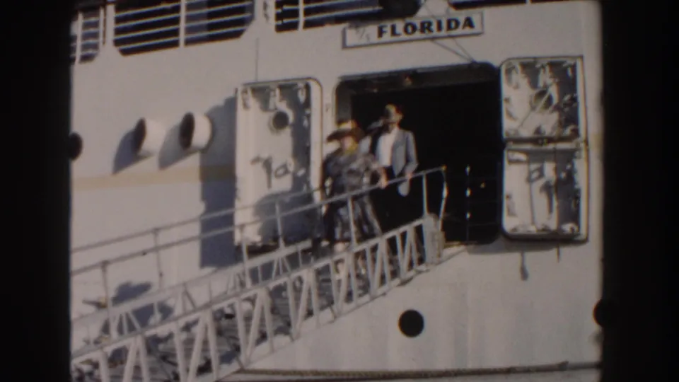 1961 Nassau home-movie frame showing adults on a gangway beside the white ship Florida in bright sun.