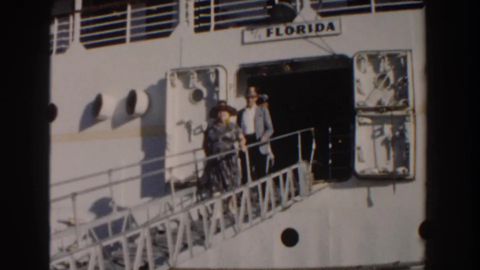 The man in a grey jacket and hat stands with a woman on the gangway of the ship Florida in Nassau, 1961.