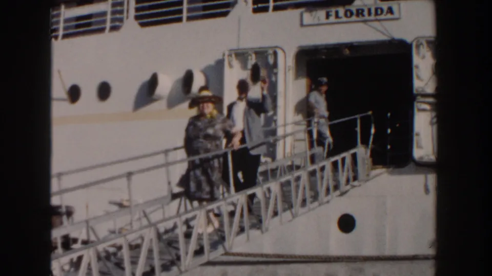 Adults on the gangway of the ship Florida move past the open doorway in bright 1961 Nassau sunlight.