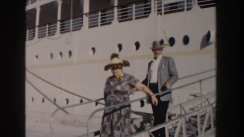 Near the lower part of the gangway, the couple walks past mooring lines and portholes on the white cruise ship in Nassau, Bahamas.