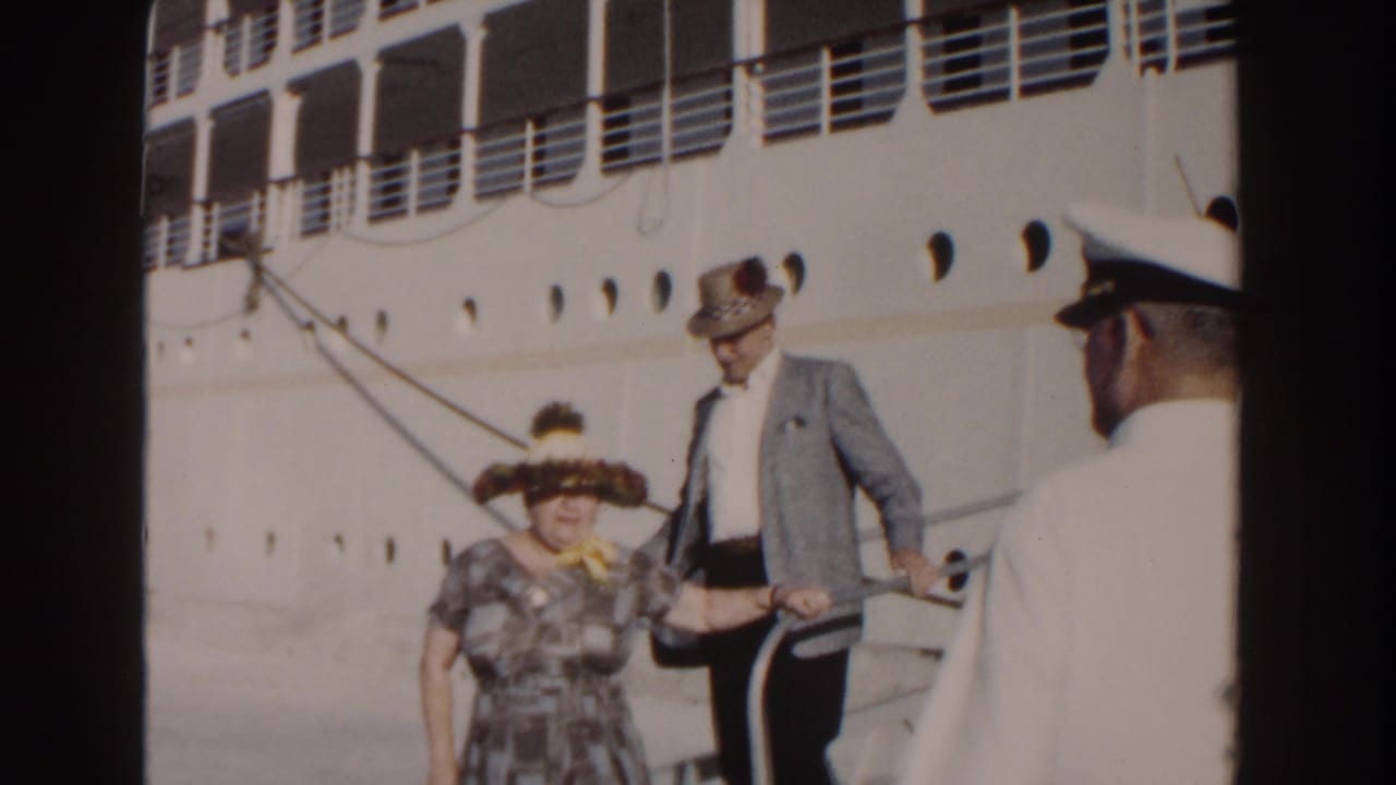 Couple on a ship gangway with a white-uniformed crew member nearby.