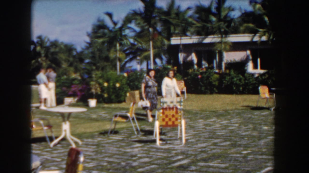 Two women walk through a bright patio area while other adults stand nearby.