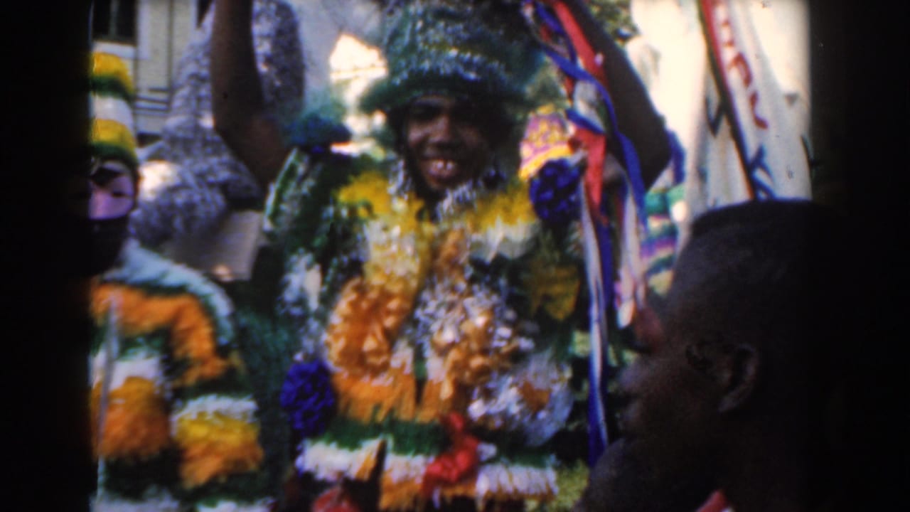 Costumed parade performer in yellow and green passes close to spectators on a street.