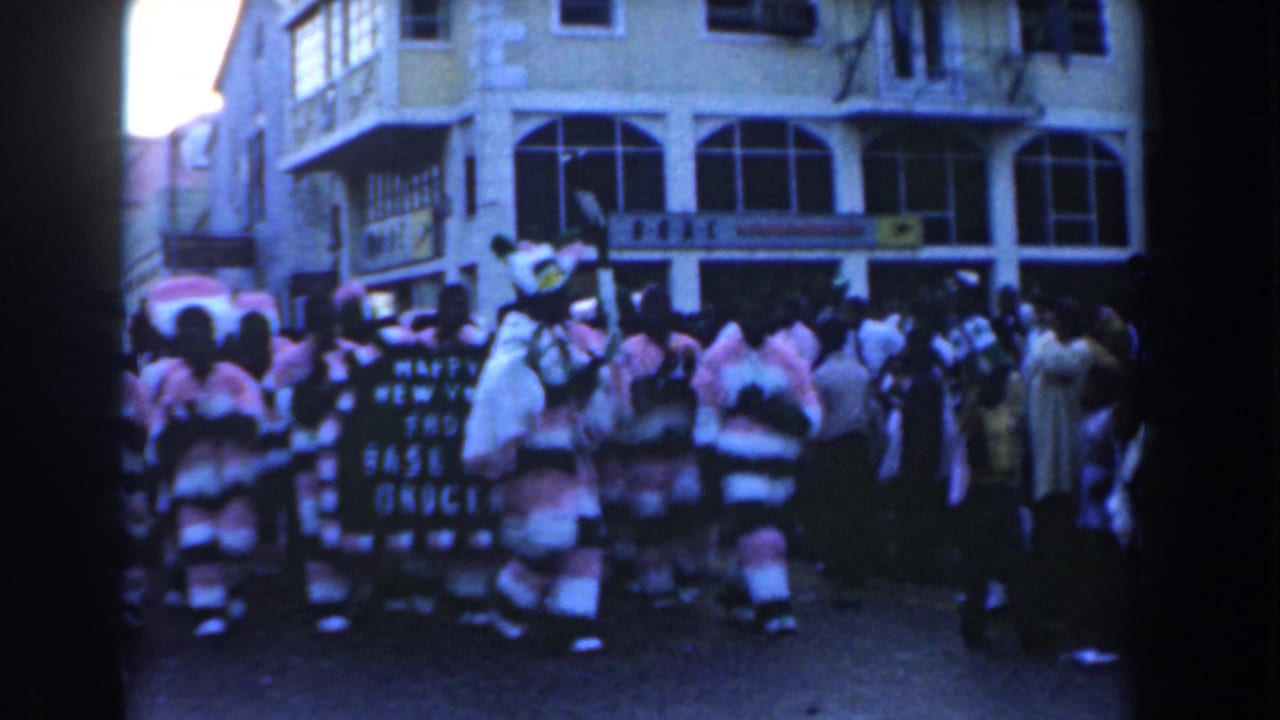 Costumed parade participants and spectators on a Nassau street.