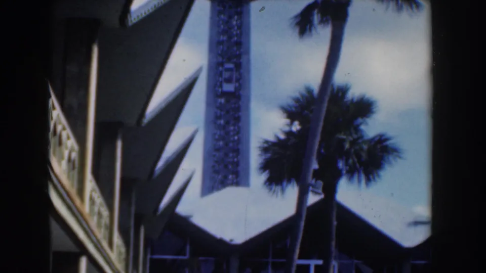 Nassau resort exterior with decorative balcony trim, white wall planes, palm silhouette, and sharp angular roof forms.