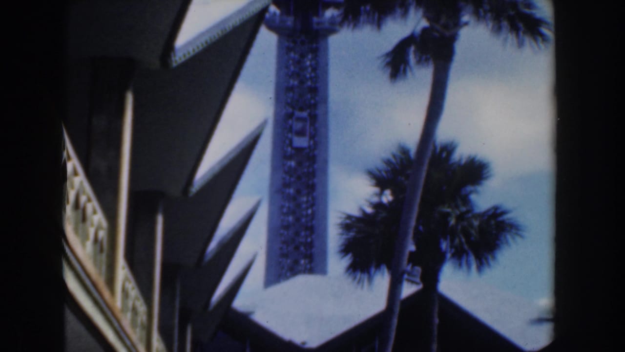 Observation tower framed by palm trees and angular building overhangs.