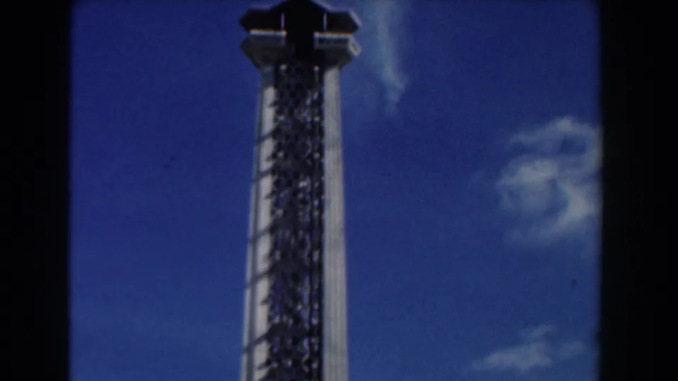 1961 Nassau frame showing the upper portion of the modernist tower, with its cap silhouetted against blue sky.