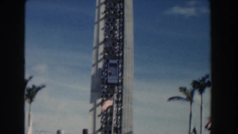 1961 Nassau 8mm frame of a tall amusement-park tower with palm trees visible near its base.