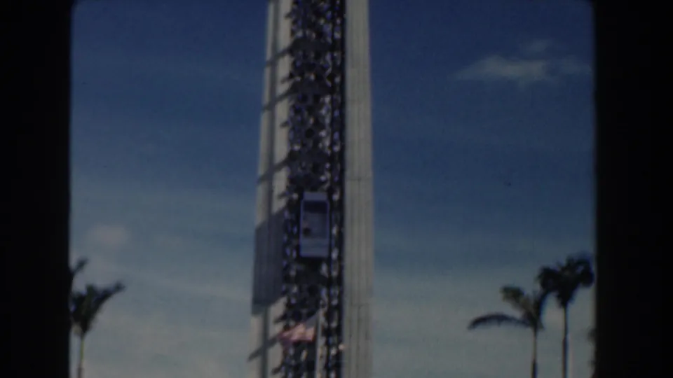 Nassau, Bahamas 1961 home-movie frame showing a tall harbor tower, palm trees, and bright sky from a handheld 8mm view.