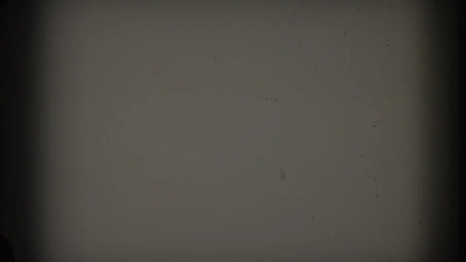 End of the blank starting section on the 1961 Nassau reel, with a pale gray field, dark film-edge bands, grain, and small specks.