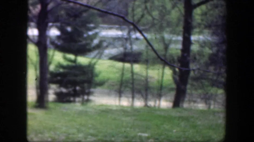 Soft 8mm view in the Cincinnati-area clip, with trees and grass dominating while the distant rider is largely obscured.