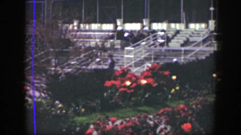 Distant figures appear among red flowers and broad railings in a Cincinnati garden scene from the stated 1949 8mm footage.