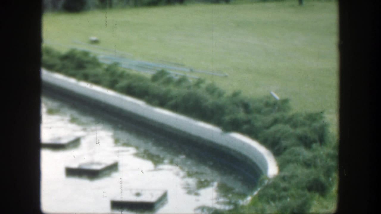 1949 Cincinnati garden footage showing a reflection pool, square stepping stones, trimmed shrubs, and open grass beyond.