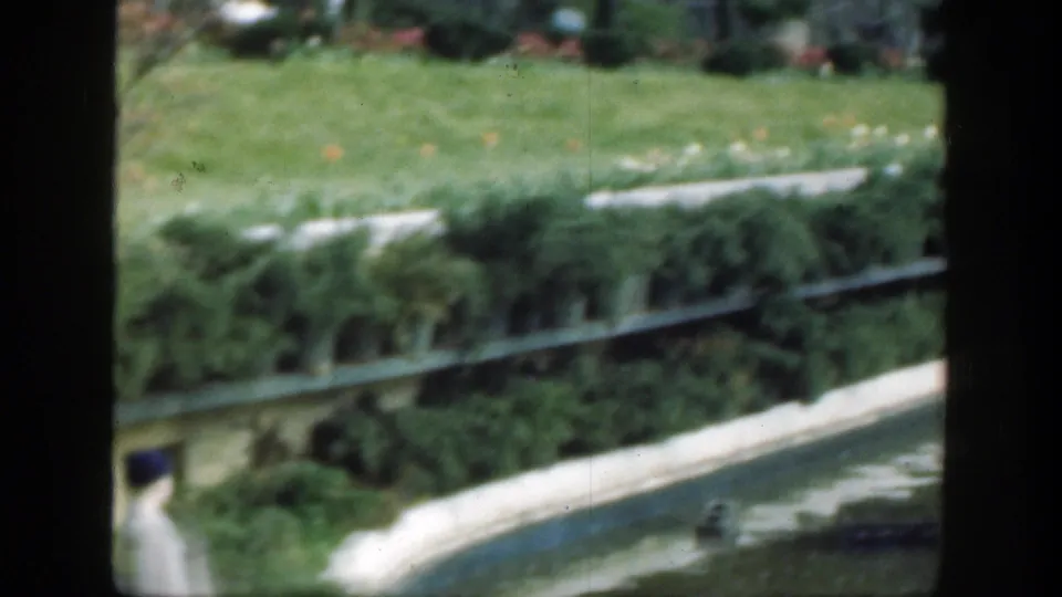 1949 Cincinnati garden detail showing a pond edge, clipped hedges, lawn, small flowers, and floating platforms on the water.