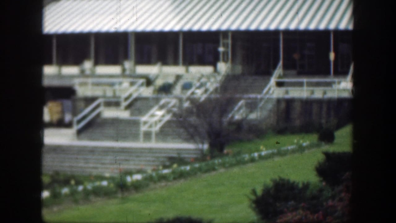1949 Cincinnati 8mm frame showing a grand building facade, striped awning, exterior stairs, railings, lawn, and planted beds.