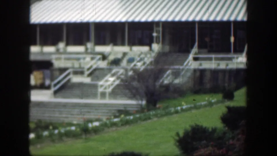 1949 Cincinnati 8mm frame showing a grand building facade, striped awning, exterior stairs, railings, lawn, and planted beds.