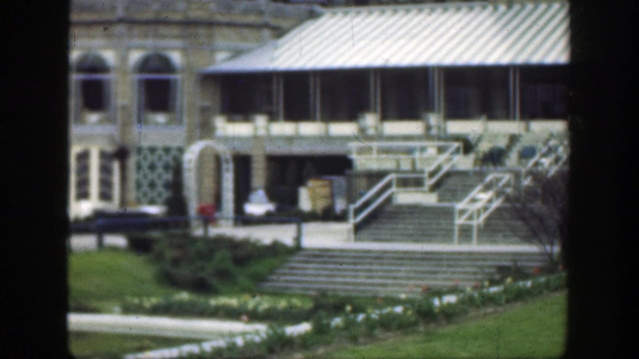 Building entrance area with arched windows, awning, steps, path, and lawn.